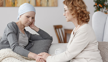 Patient sitting with friend or family member, holding hands. It looks like a tense, difficult moment.