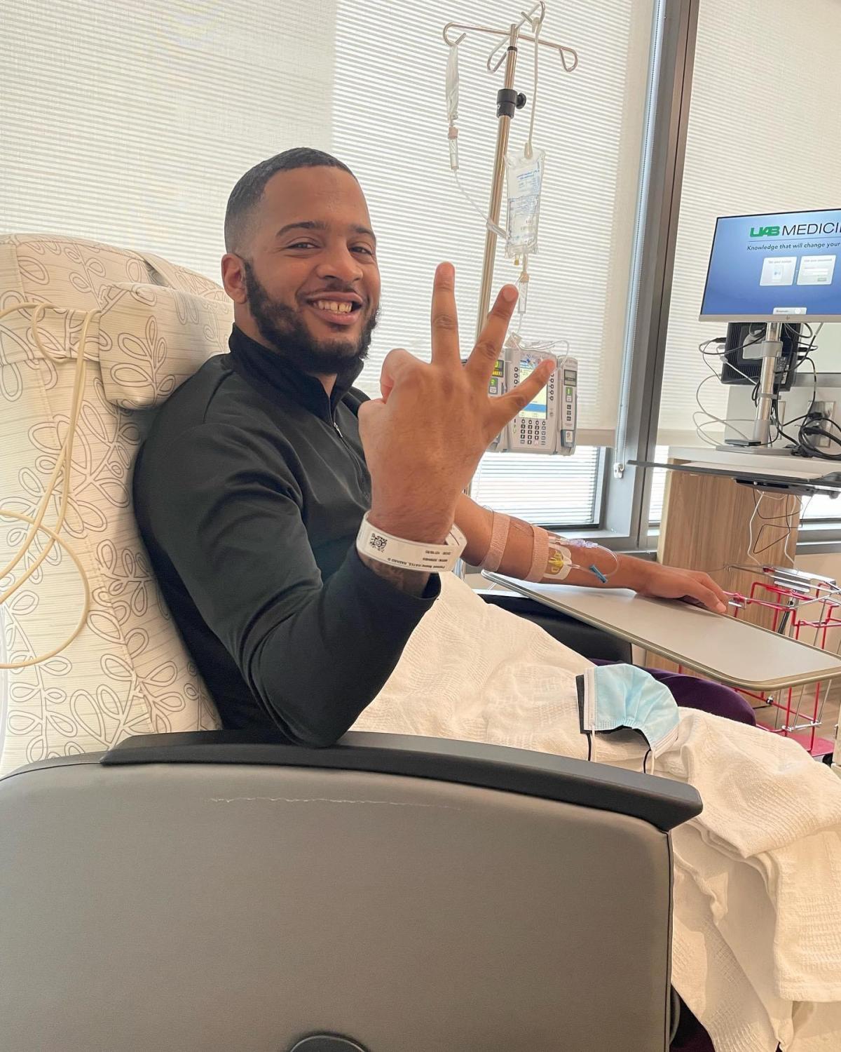 Rashad receiving treatment, holding up three fingers, smiling