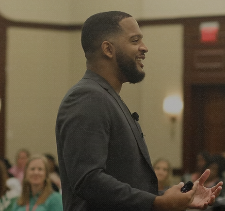 Rashad speaking in front of a crowd, side profile