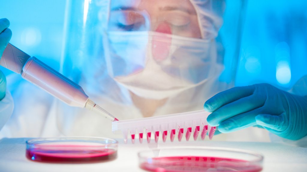 Scientist in face mask and shield sampling blood