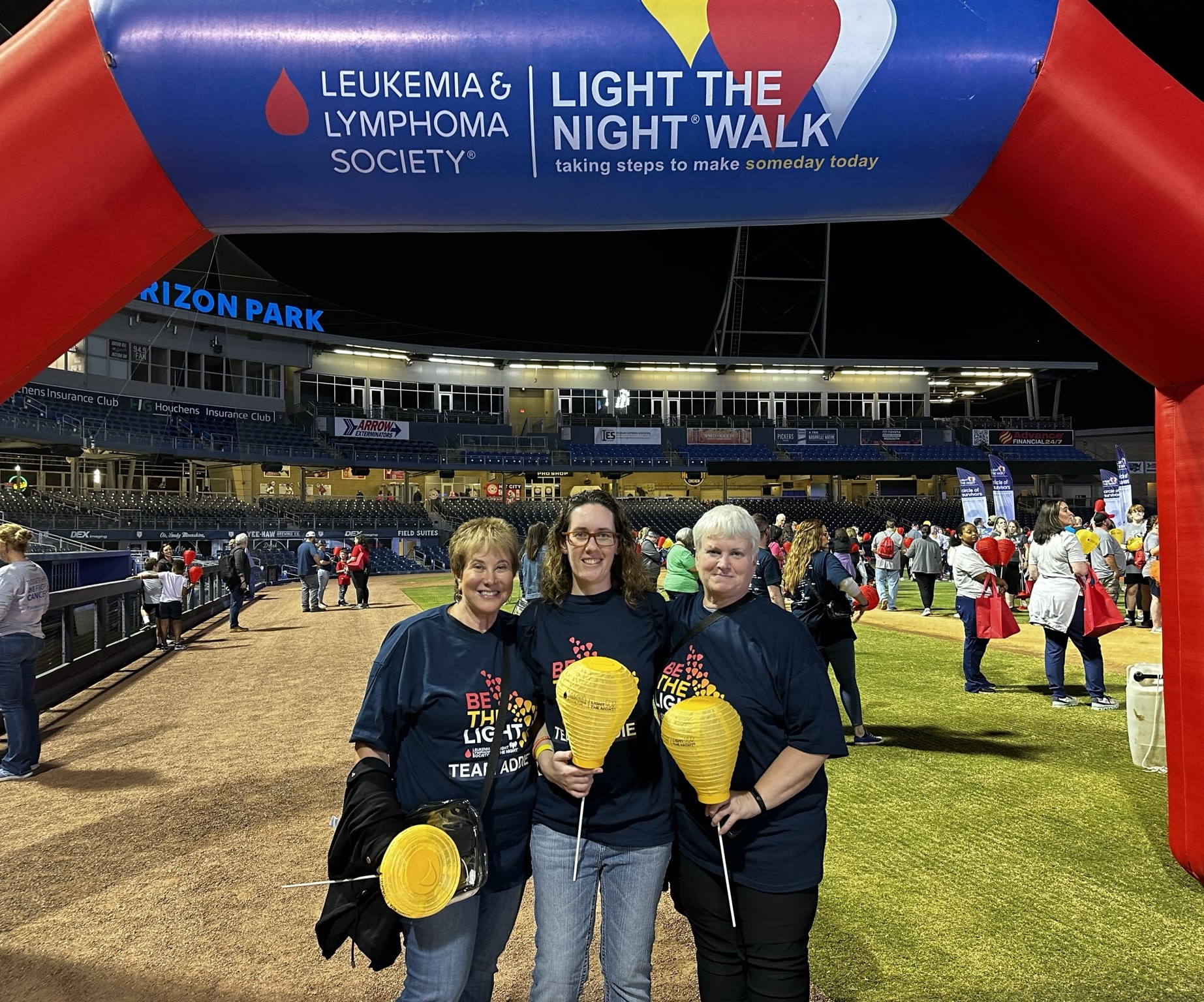 three white women holding gold balloons middle one with glasses all wearing LTN tshirts