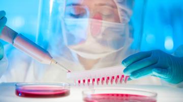 Scientist in face mask and shield sampling blood