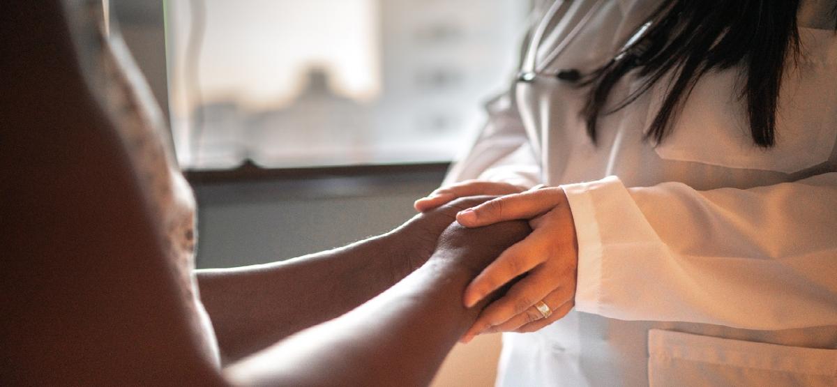 Doctor in white coat holding a patient's hands